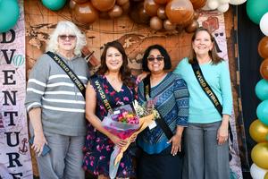 Four WVUSD retirees smile in front of an “Adventure Awaits” photo wall.
