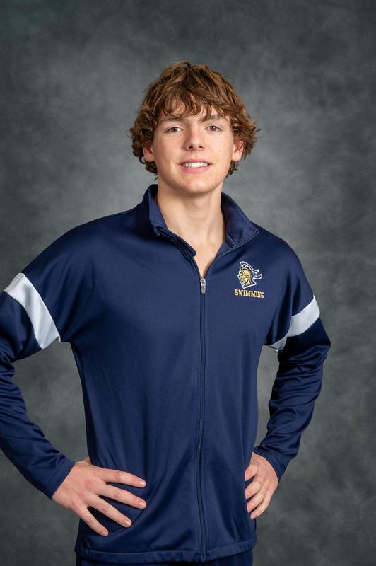 boy swimmer with curly hair smiling at camera in swim warm-up