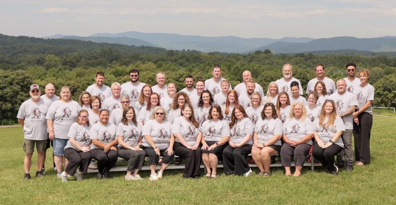 Group of people posing together outdoors with mountains in the background.