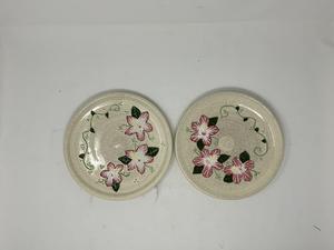 Two painted plates with white and pink flowers on them.