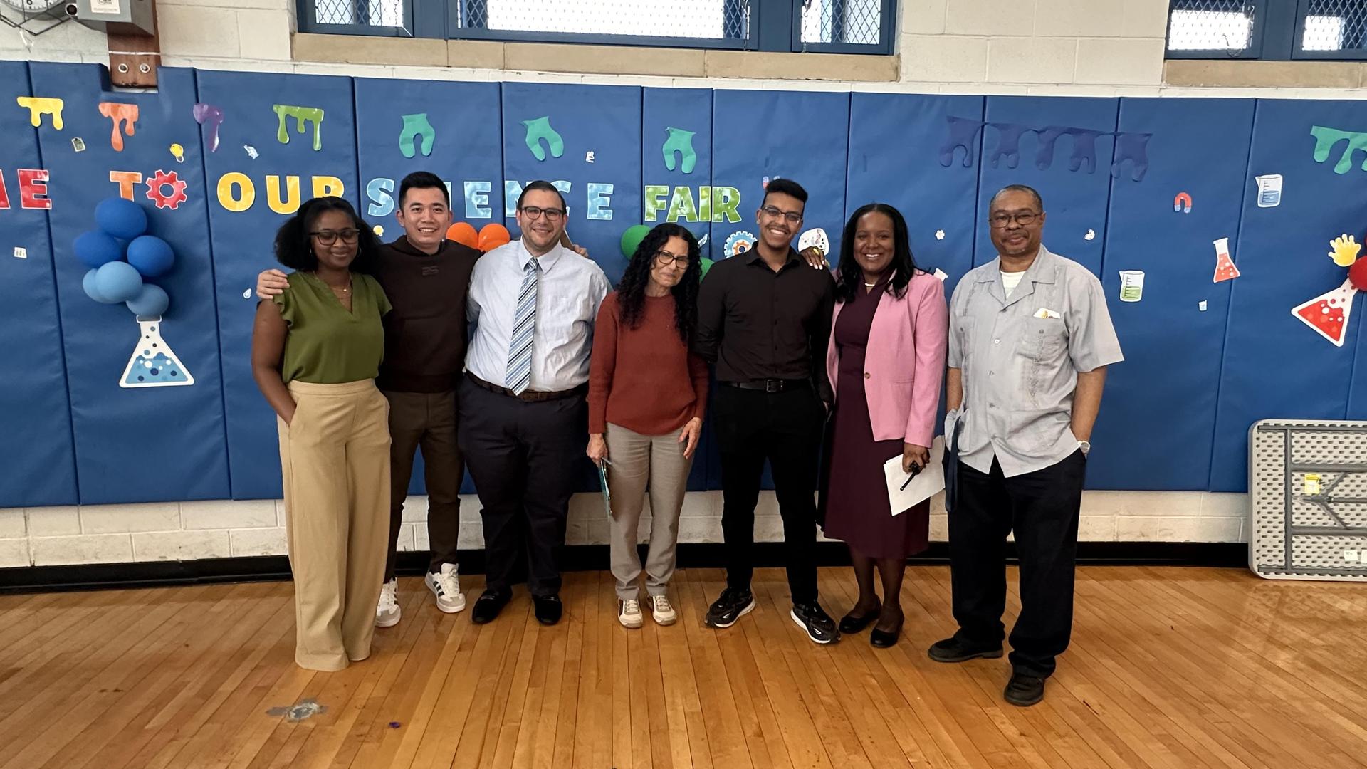 A group of seven people posing for a photo at a science fair event.