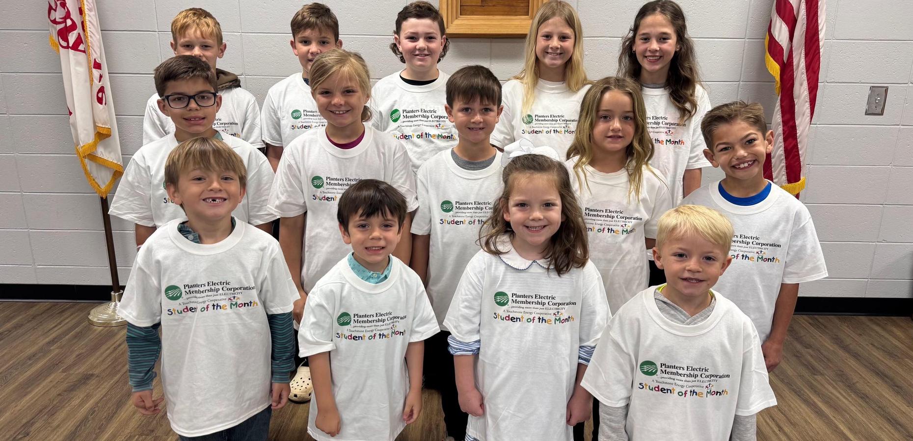 Group of children wearing matching t-shirts, smiling at an event.