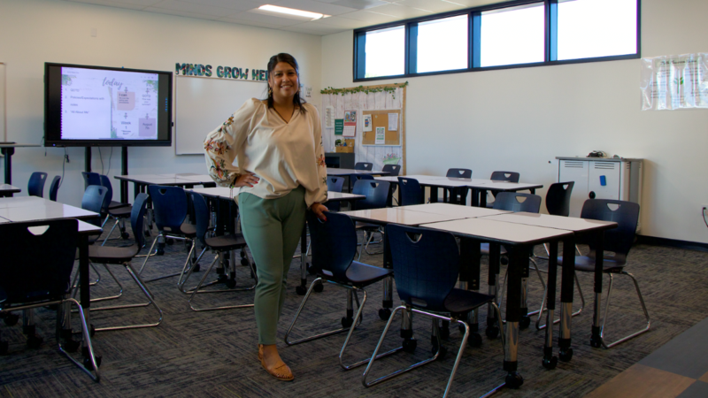 Ms. Romero stands in front of the new classroom of desks.