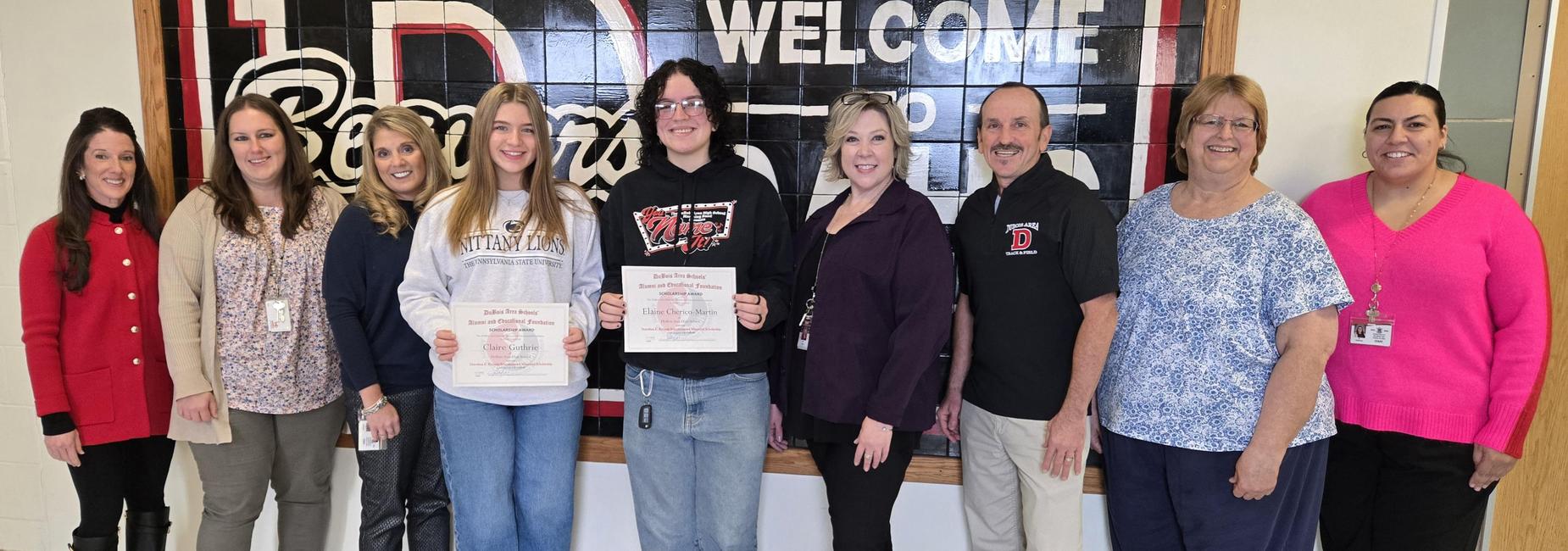 Group of people smiling in front of a welcome sign. DASAEF presented the Dorothea E. Kyriazis Scheidemantel Memorial Scholarship to Claire Guthrie and Elaine Cherico-Martin