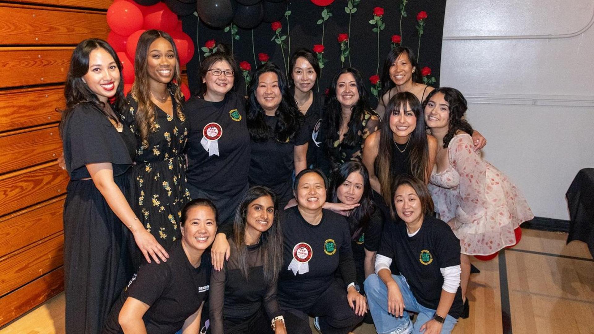 A group of women posing together at an event, with festive decorations in background.