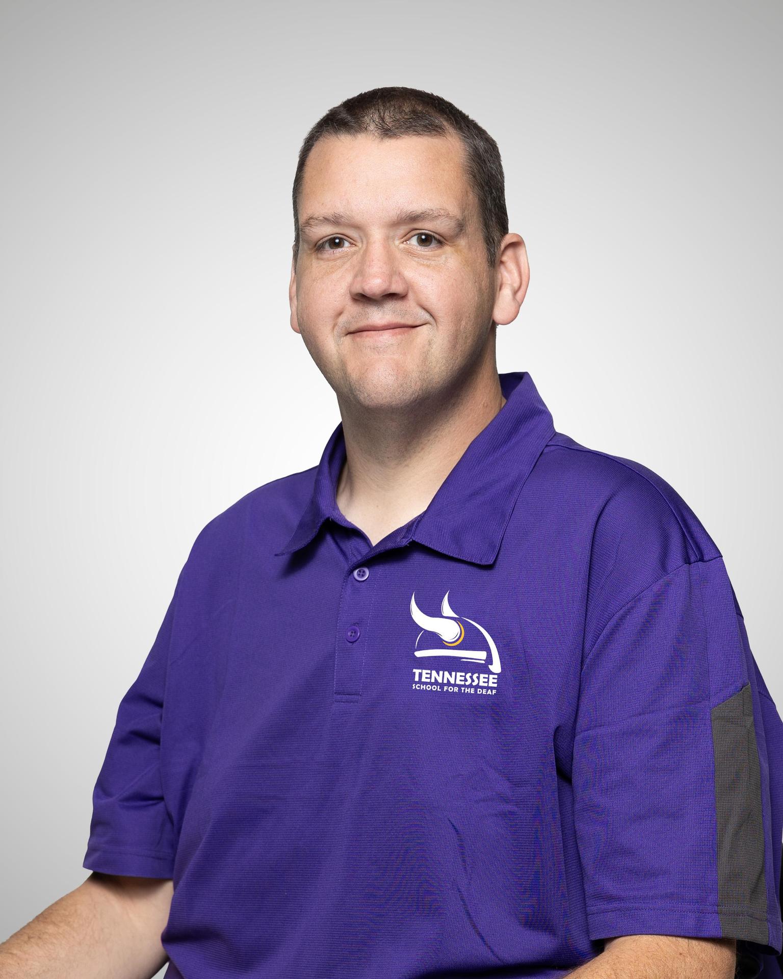 Man wearing a purple polo shirt with the Tennessee School for the Deaf logo.