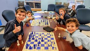 The boys enjoy playing chess against each other.