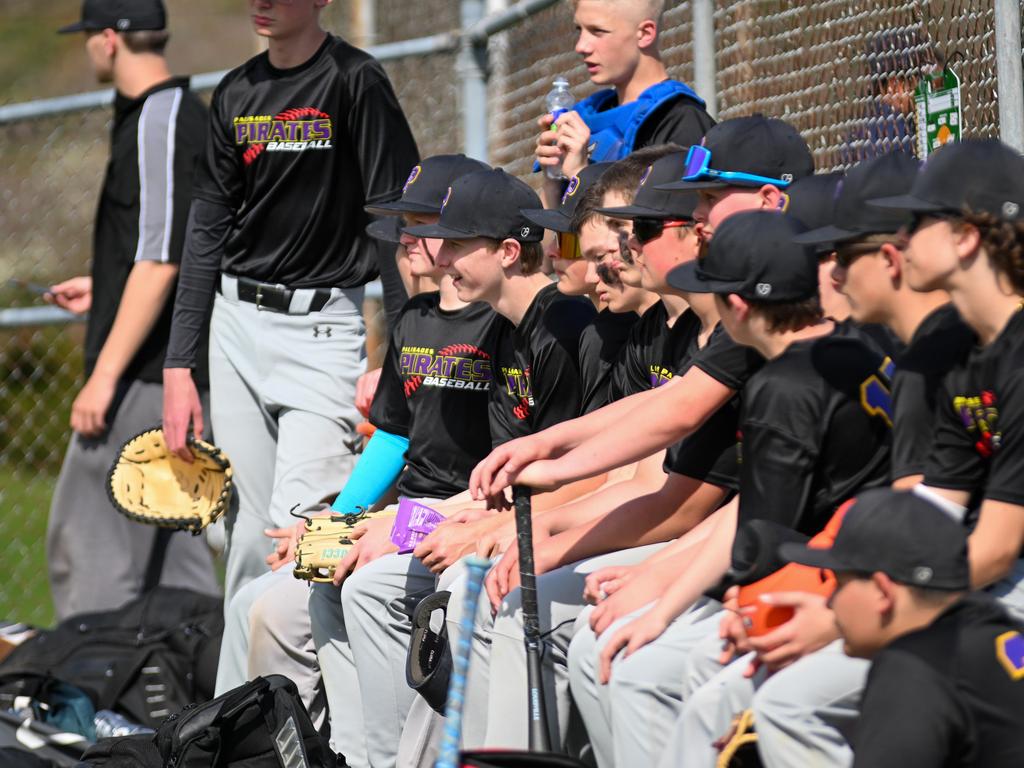 The baseball team sitting on a bench in the dugout.
