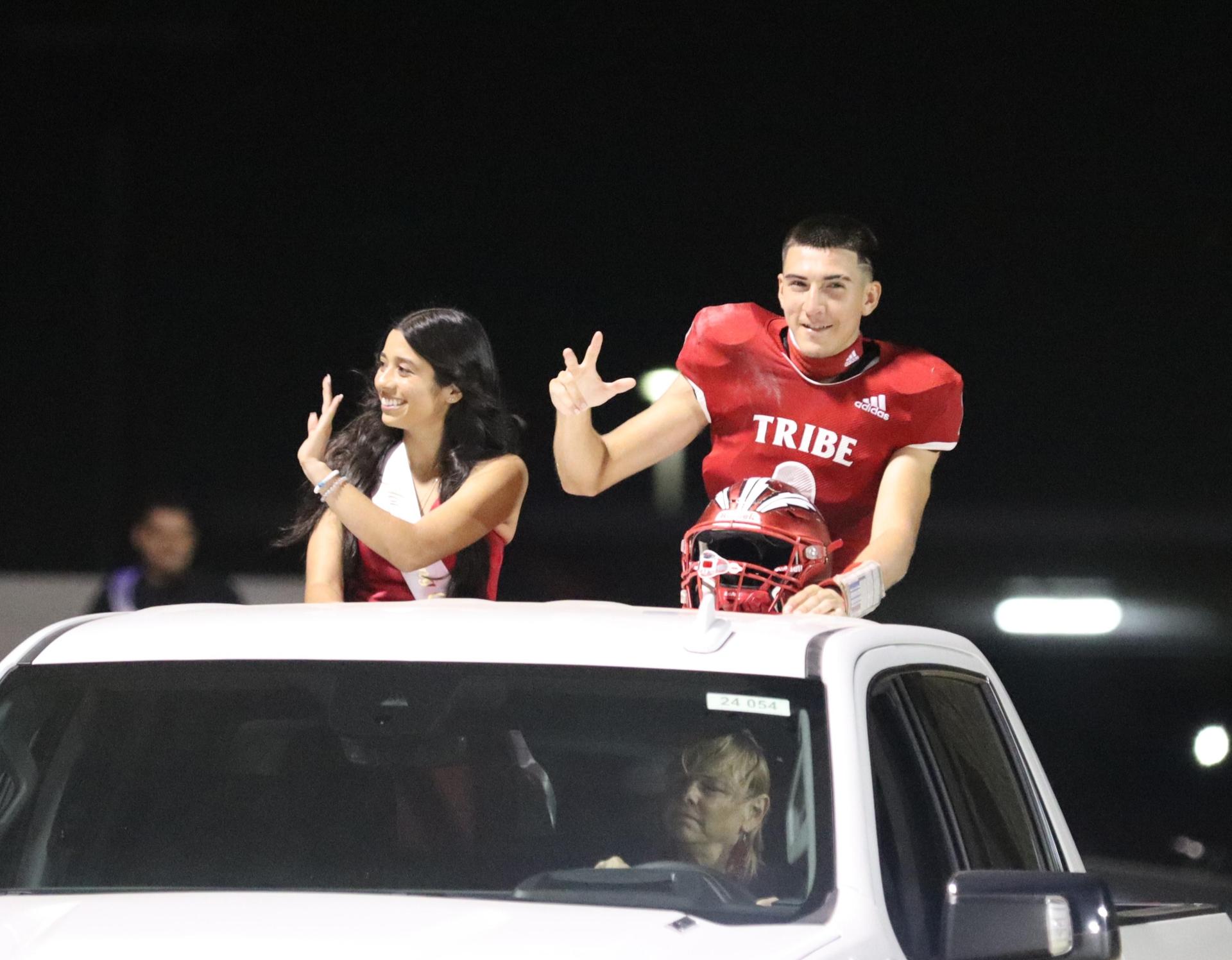 homecoming king and queen candidates entering the stadium in trucks