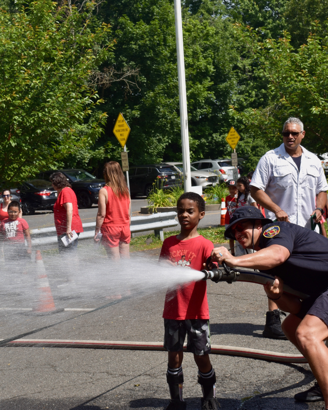 Firefighter shows student how to work the fire hose