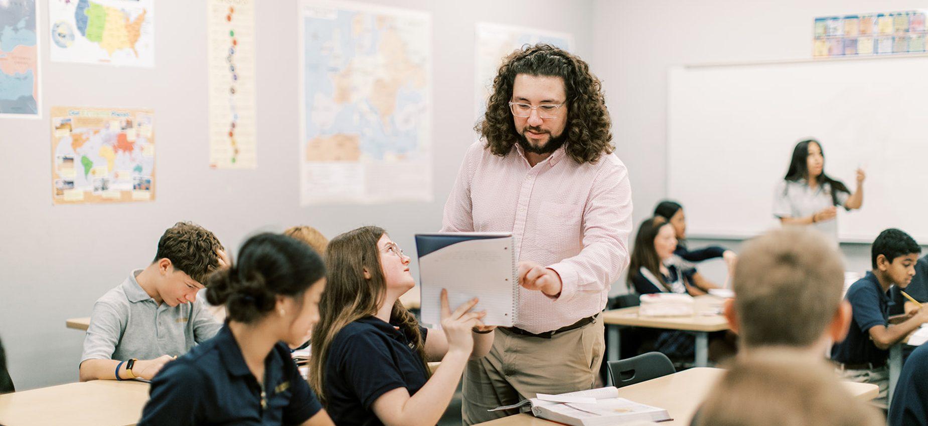 A teacher holds up a book as he teaches his class