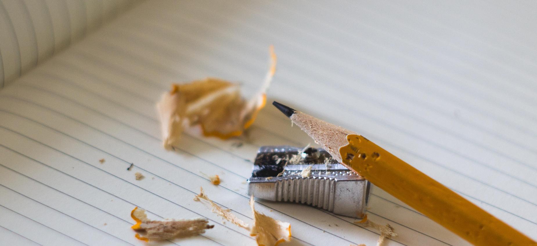 Sharpened pencil and shavings on lined notebook pages.