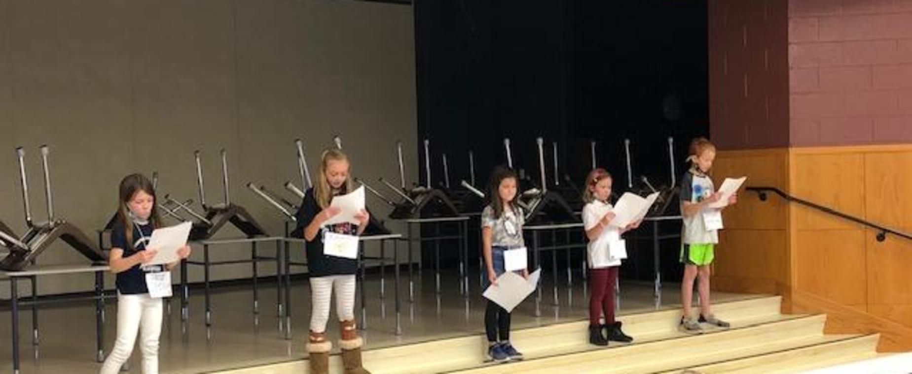 Second grade presents their stories to an audience of kindergarteners.