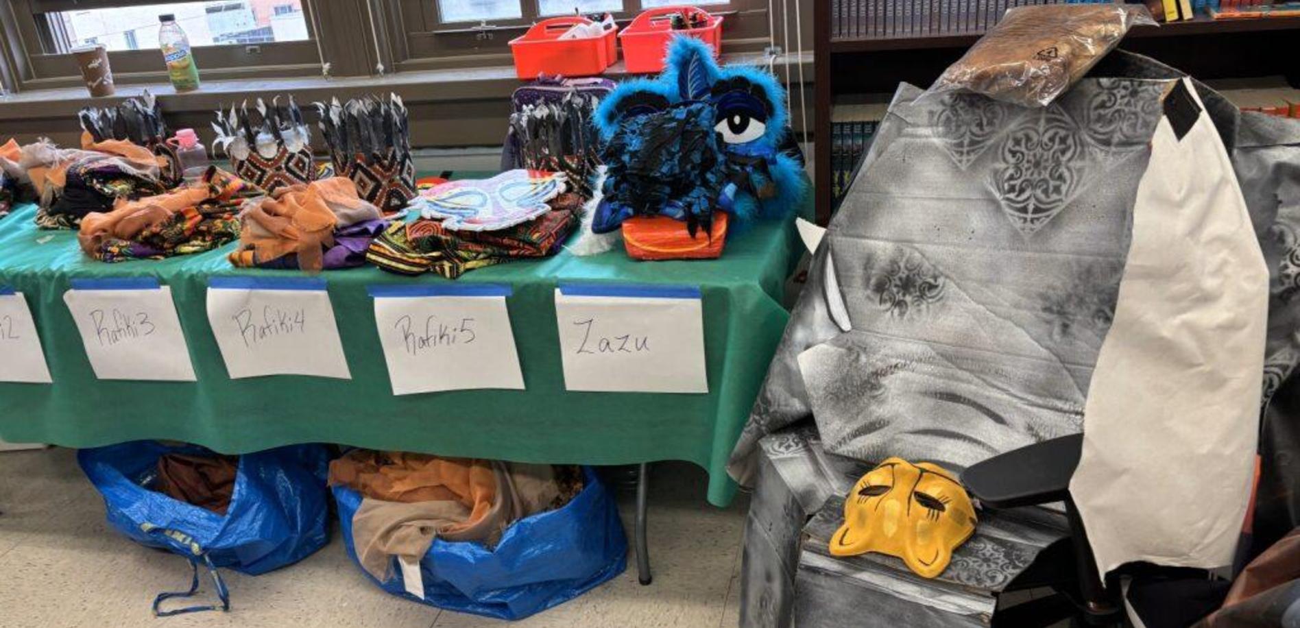 A table with colorful costumes and props, including masks and fabric pieces.
