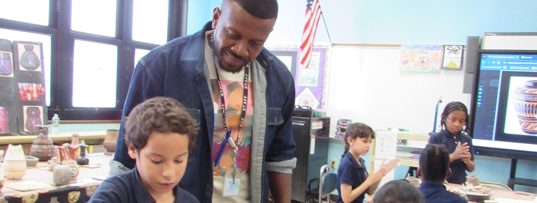 Students engaged in a pottery lesson with a teacher in a classroom.