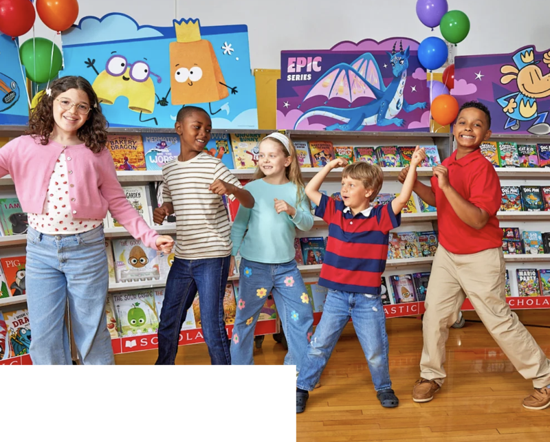 kids smiling and standing in front of books