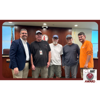 Photo of 4 men standing in front of the board dais