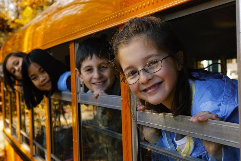 photo of bus with kids looking out window