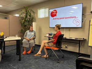 Two participants share conversation at front of class