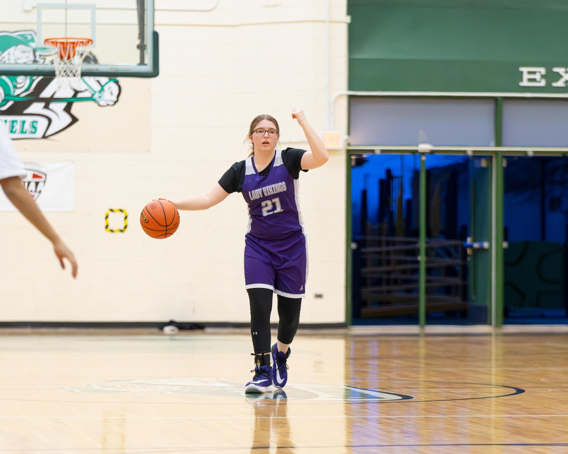 Girls basketball player bouncing the ball up the court