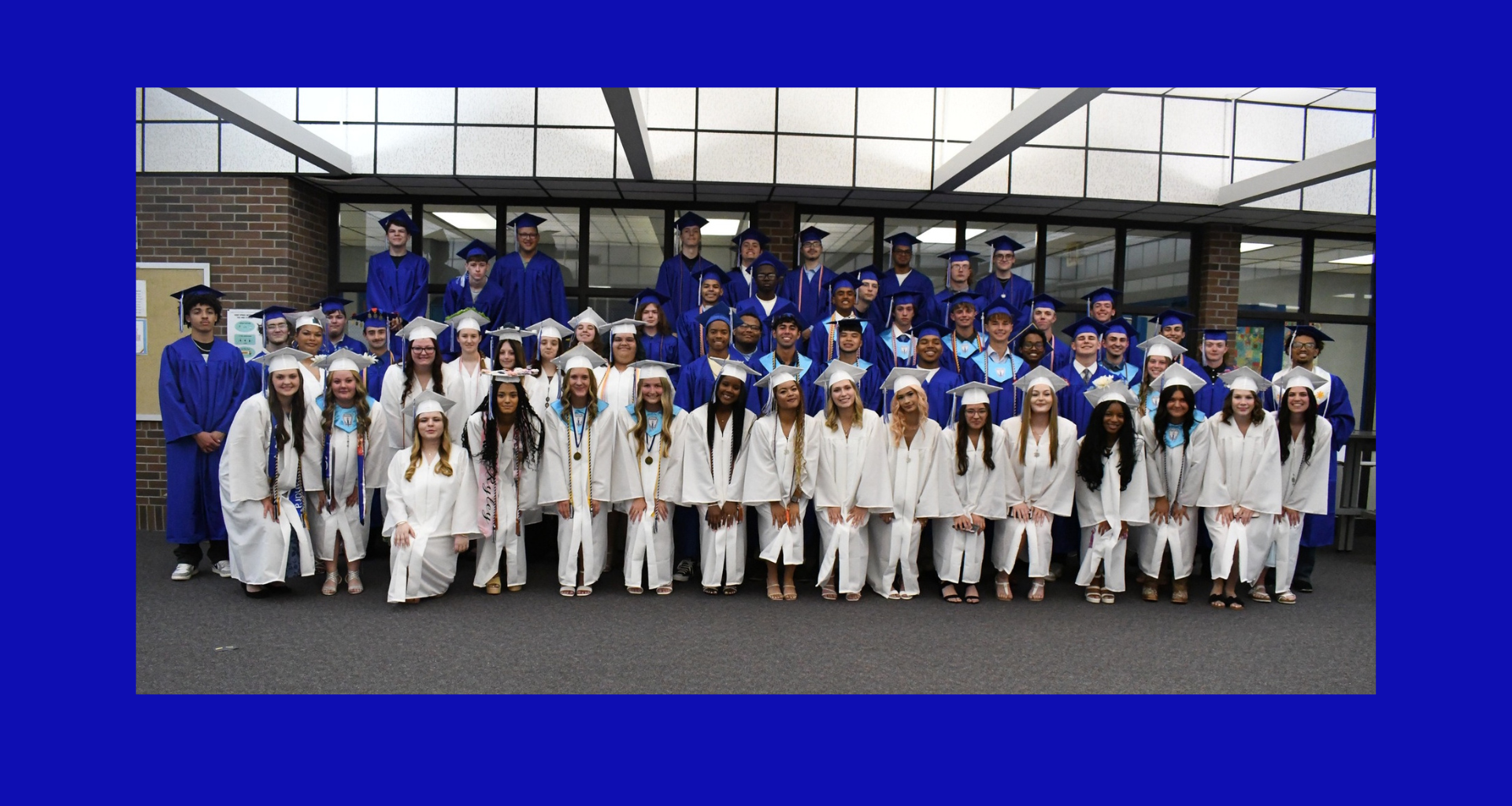 Graduating class in caps and gowns posing together indoors.
