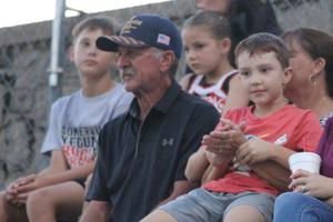 Spectators, including children and adults, sitting in the stands at a game.