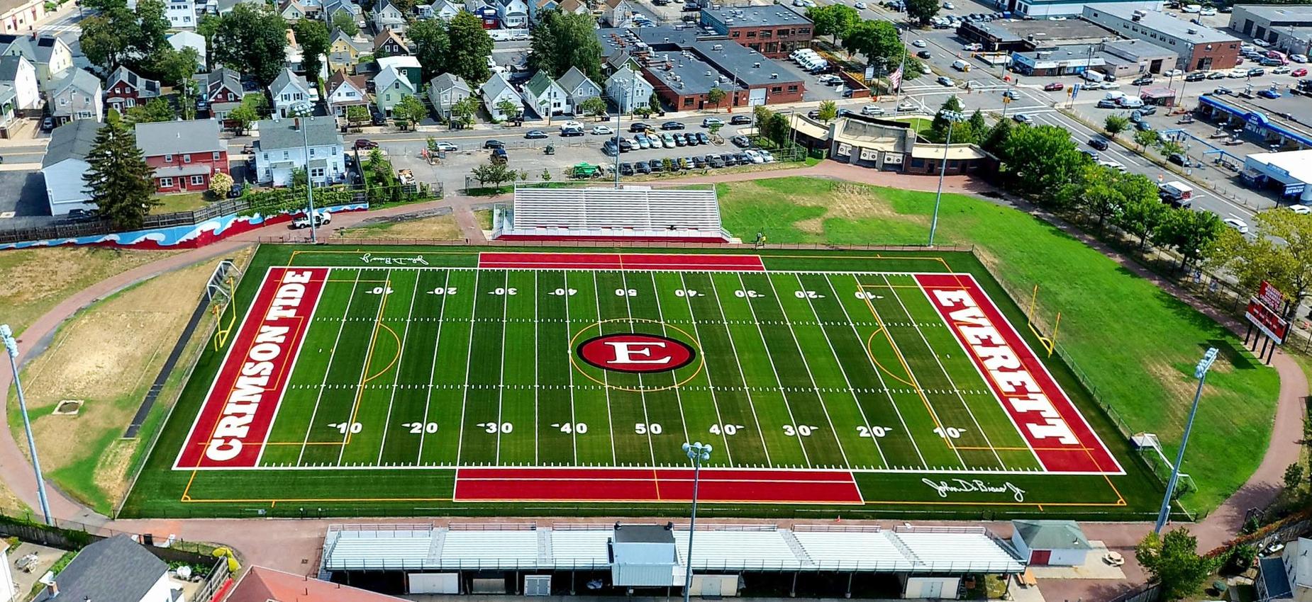 Aerial view of a sports field surrounded by a cityscape and residential areas.