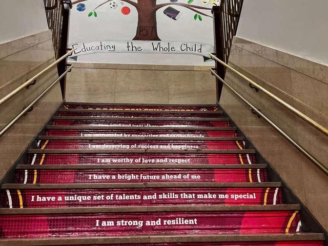 Stairs adorned with motivational quotes and a mural of a tree.