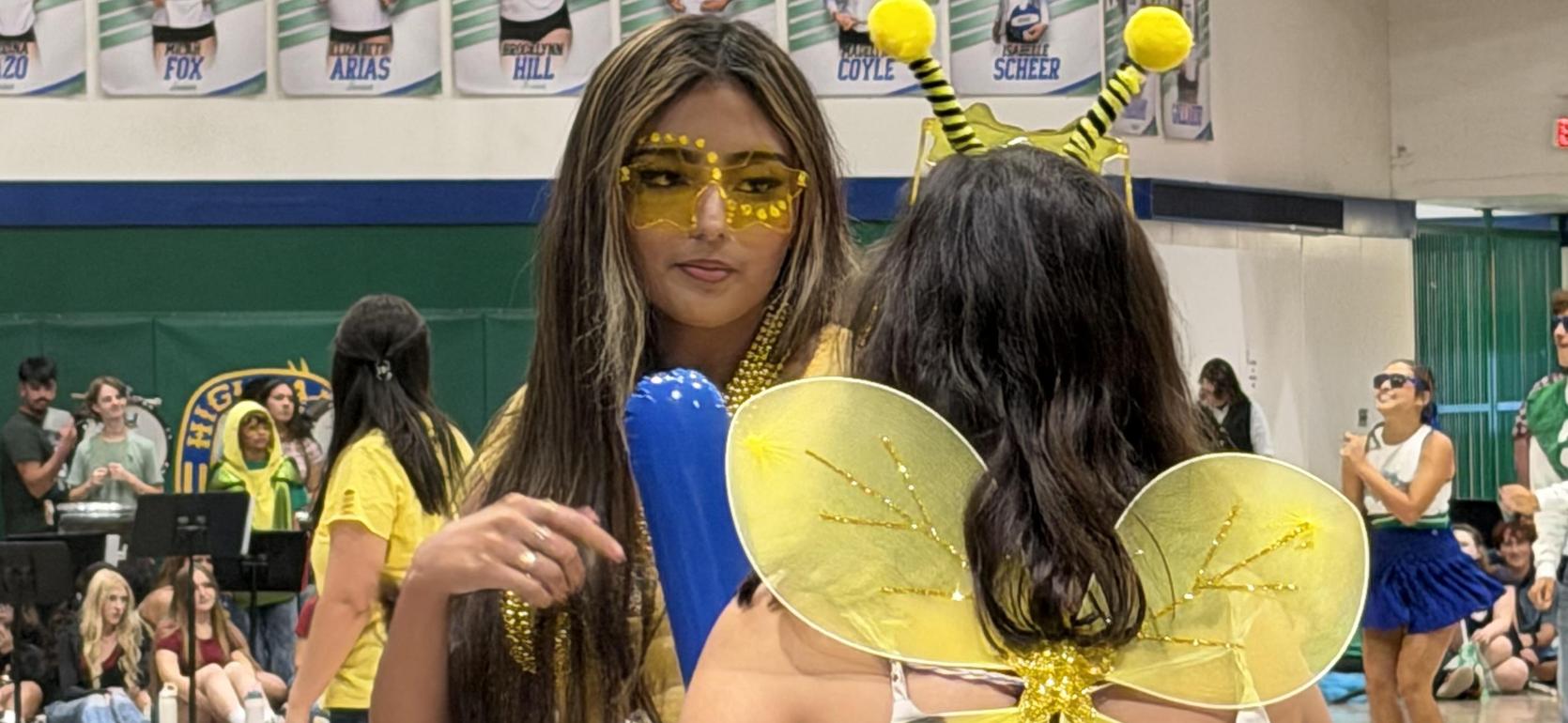 Two students in playful costumes interact during a school event.