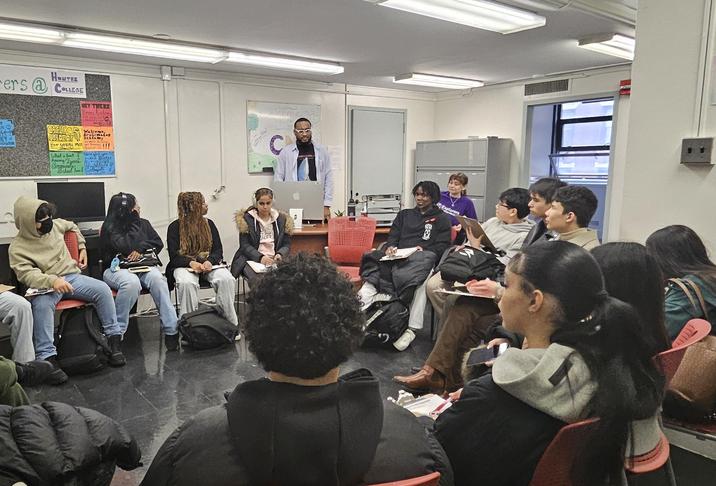 Group of diverse students engaged in discussion in a classroom setting.
