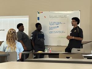 Boys presenting at a dry erase board