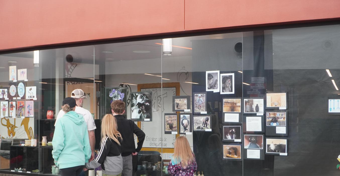 Visitors look at the artwork displayed in the art classroom windows during the art festival.