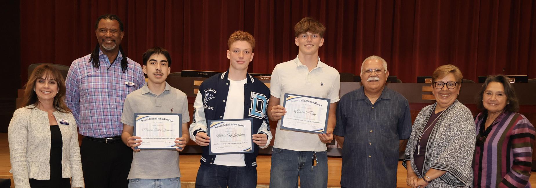 Group of six people posing with certificates in a formal setting.