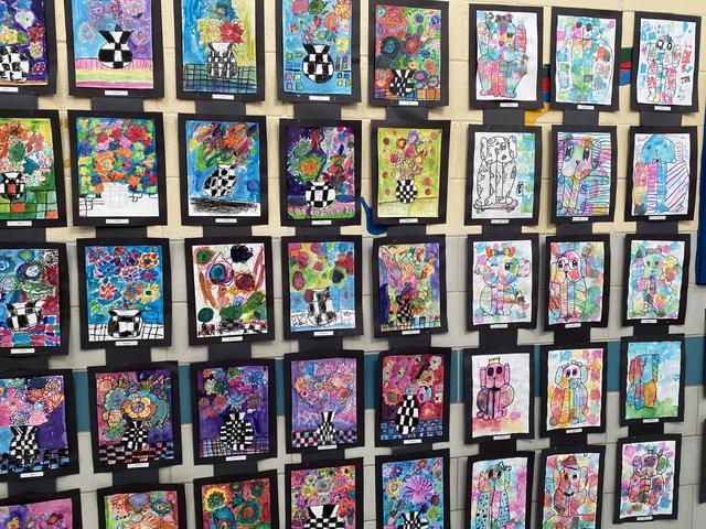 A vibrant display of colorful children's artwork in frames on a wall.