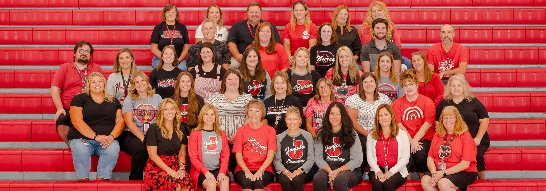 Juniata faculty and staff wearing red and black posing on red bleachers.