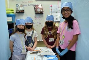 Students in surgical caps pose together in a classroom activity.
