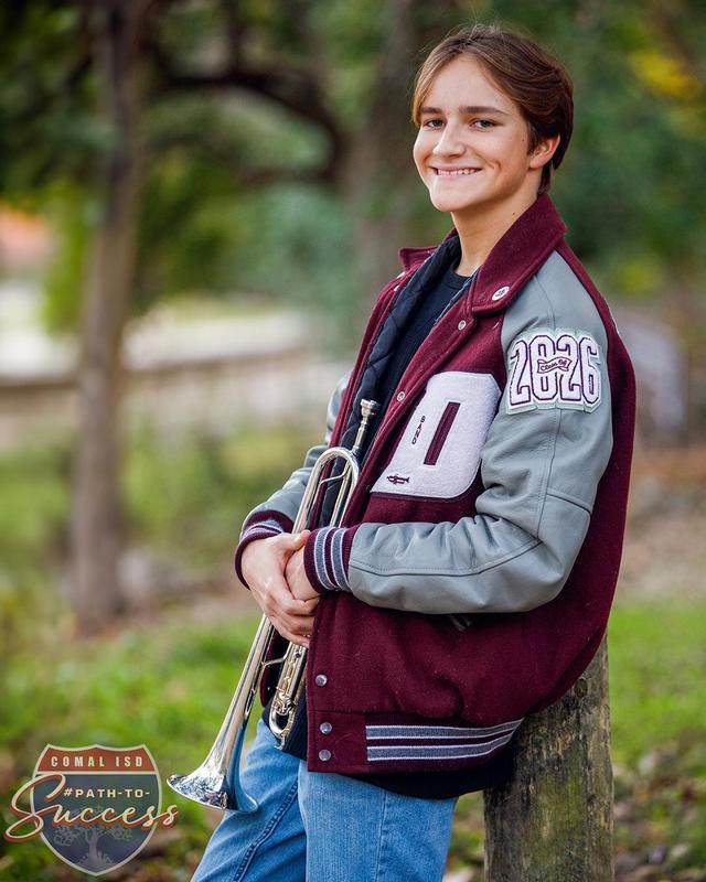 Davenport High School senior Caleb Atkins wearing his varsity jacket and holding his trumpet.