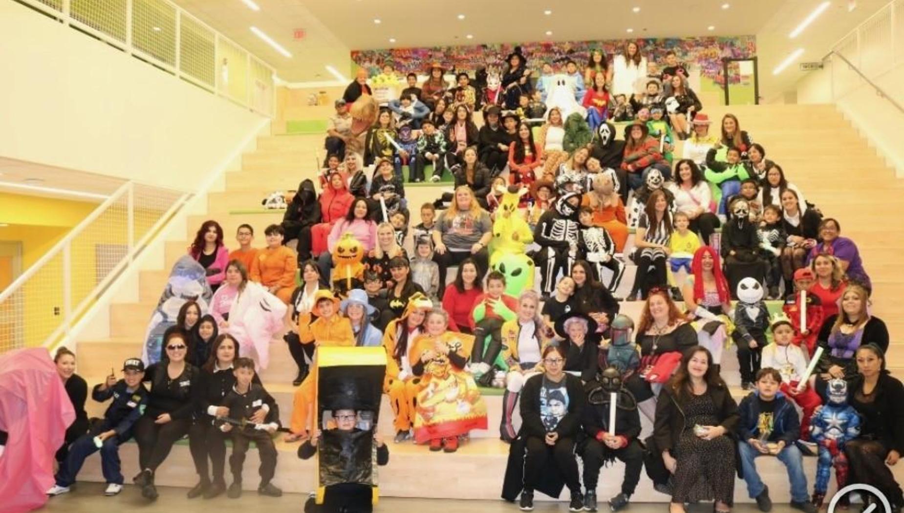 A large group of people in various Halloween costumes posing on a staircase.