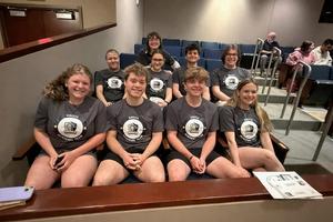 students sit in auditorium dressed in trivia team shirts