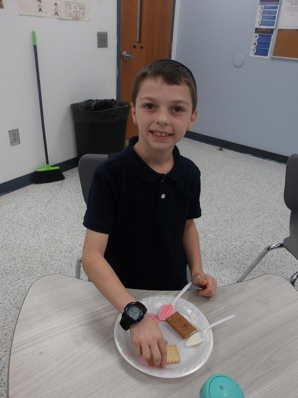 a fourth grade student spreads frosting on his shofar sandwich