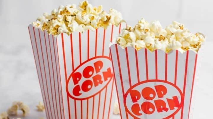 Two striped popcorn containers filled with buttery popcorn.