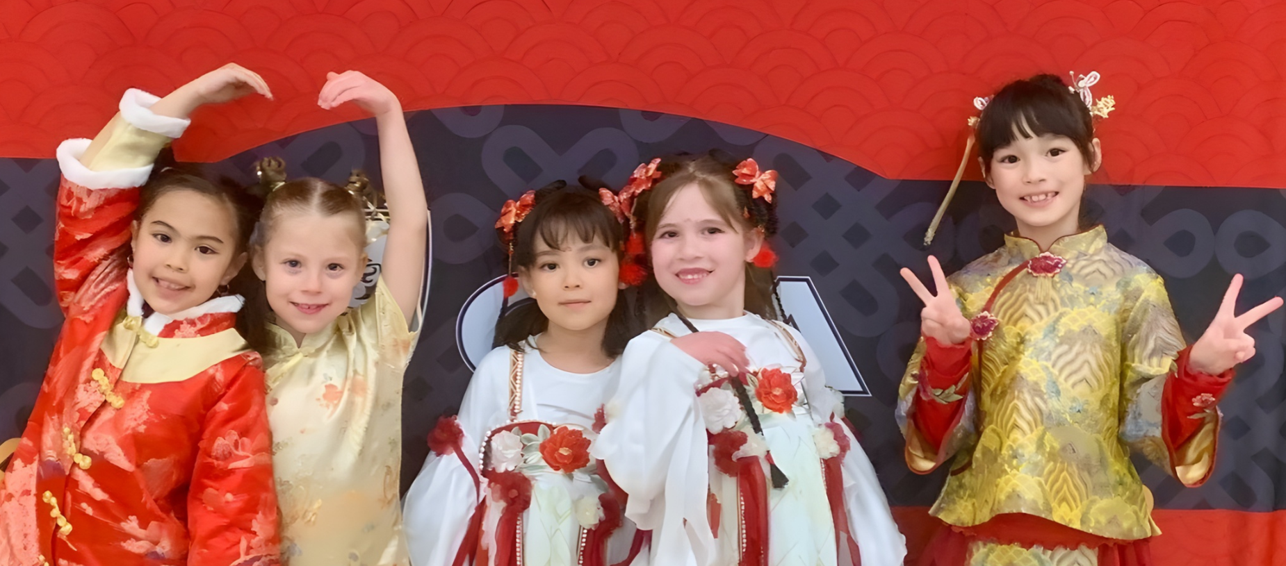 Five girls in traditional Chinese dresses pose against a decorative red background.