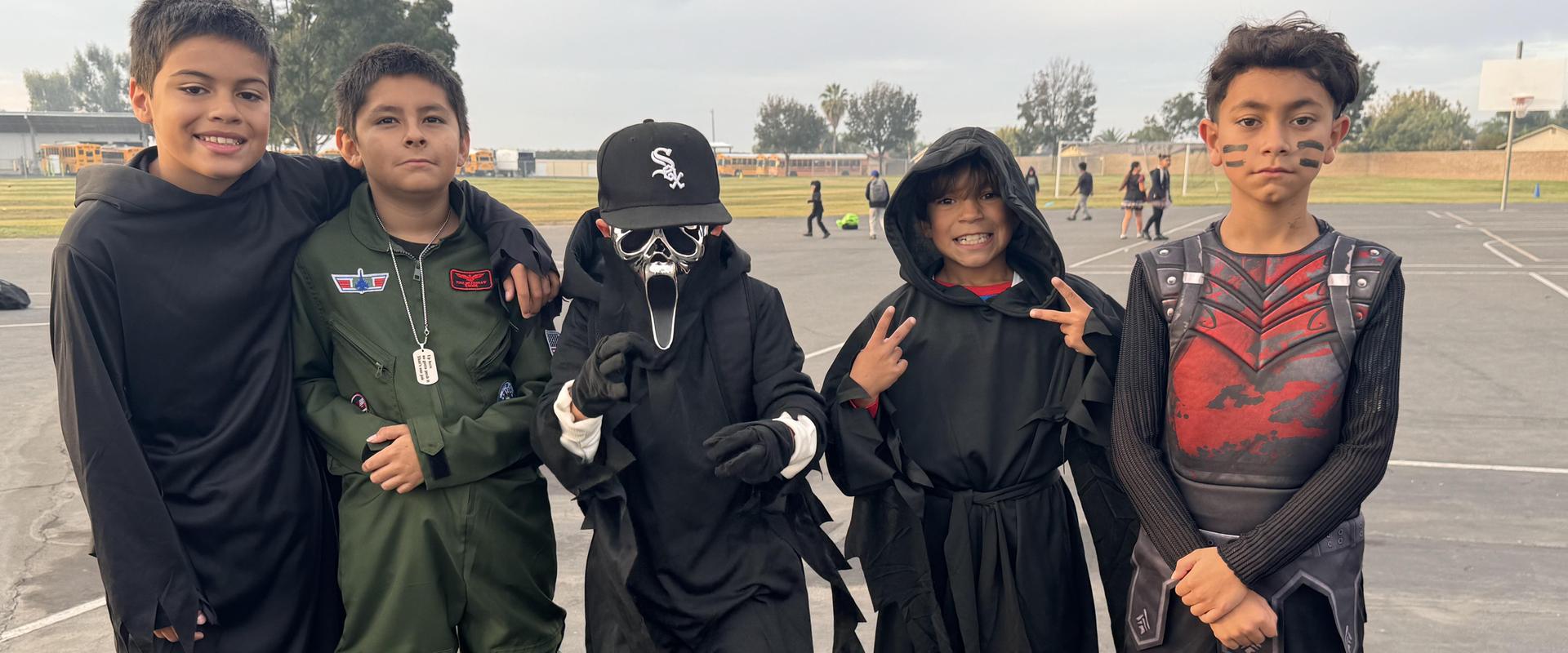 Five children in costumes posing together outdoors.