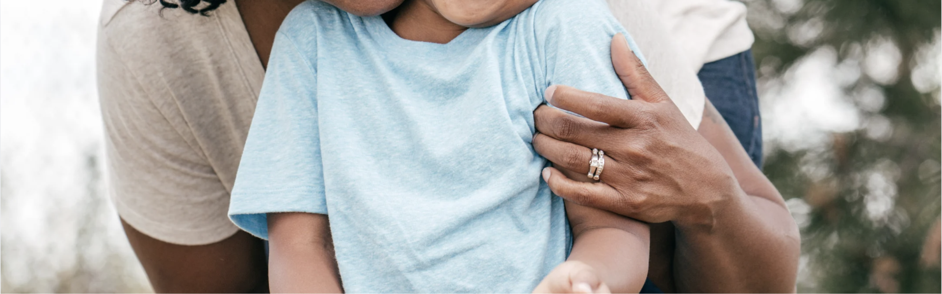 A Black woman gently holds a childs arm.