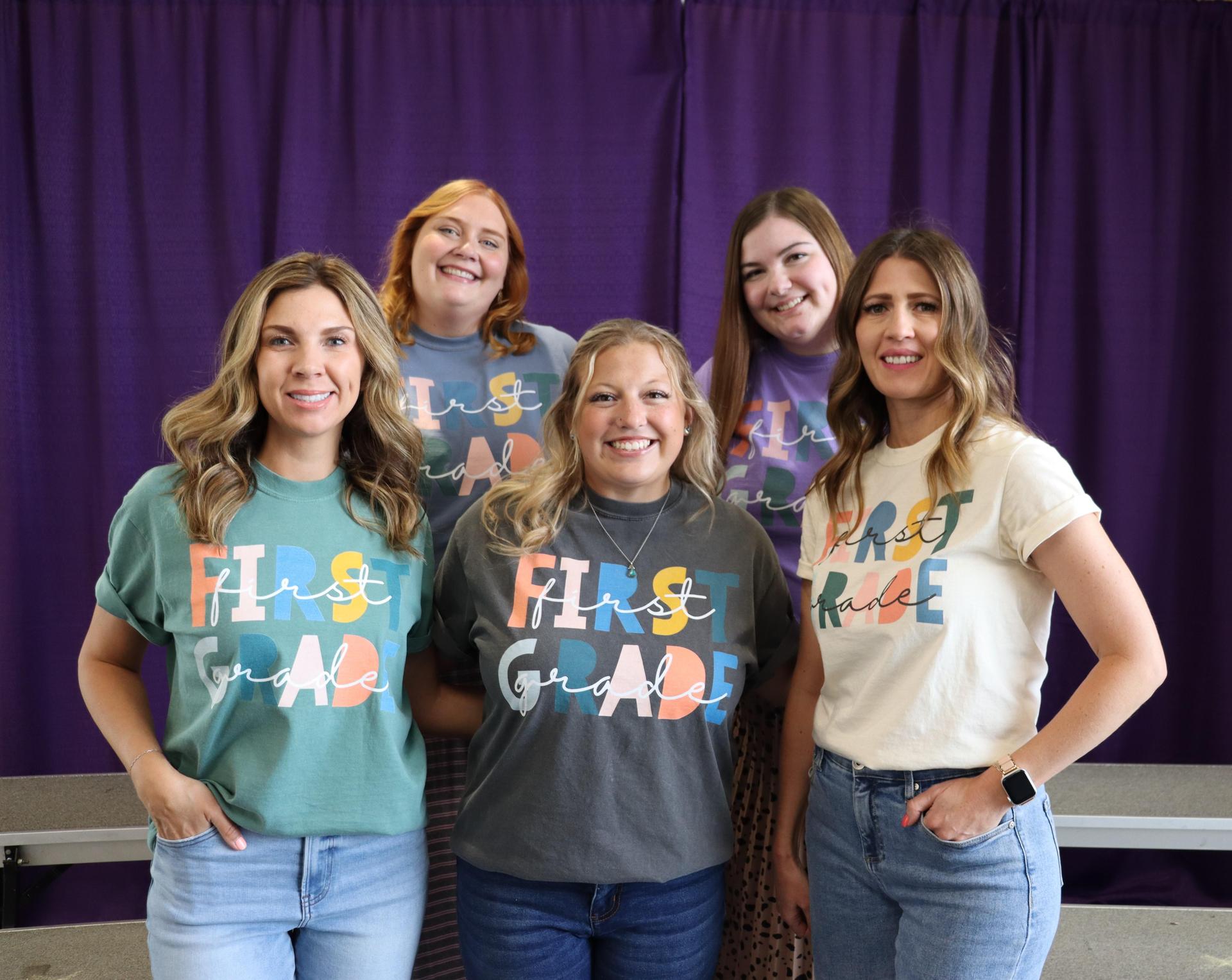 First grade teachers smiling together with a Stargate purple background.