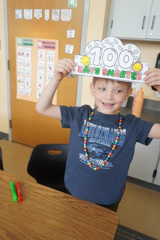 A student holds up the crown he is making for 100th day.