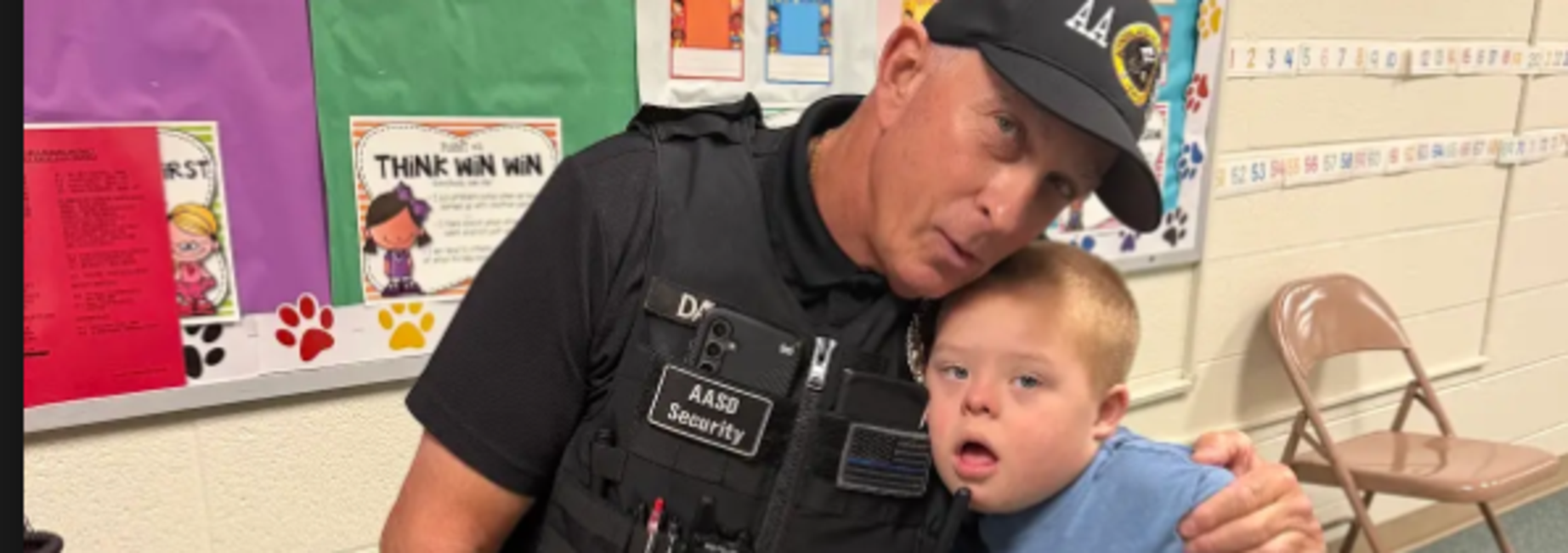 A security officer sitting with a young boy, both smiling and sharing a moment.