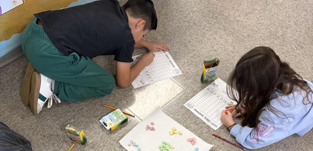 Children engaged in a floor activity with colorful cereal pieces and worksheets.