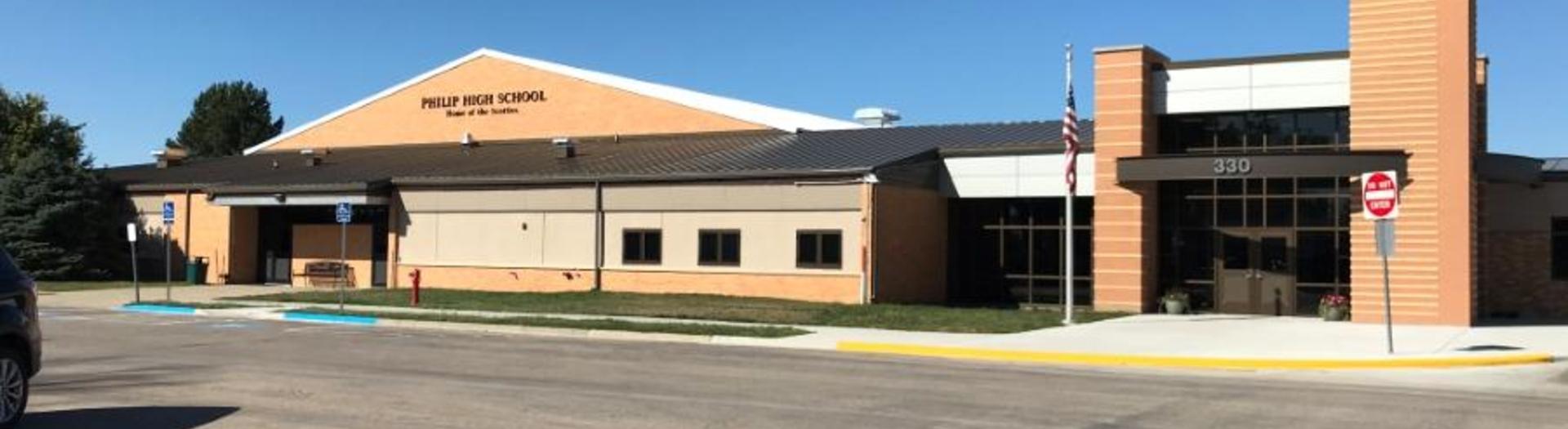 Exterior view of Phillip High School with a flag and entrance.
