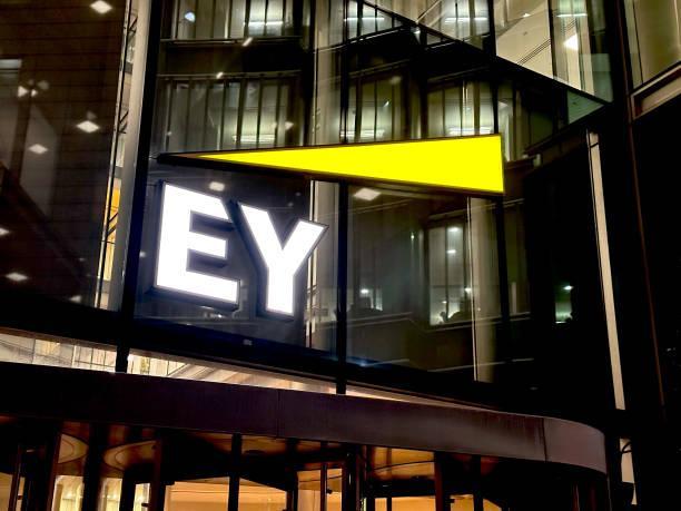 Exterior of a modern building featuring the EY logo illuminated at night.
